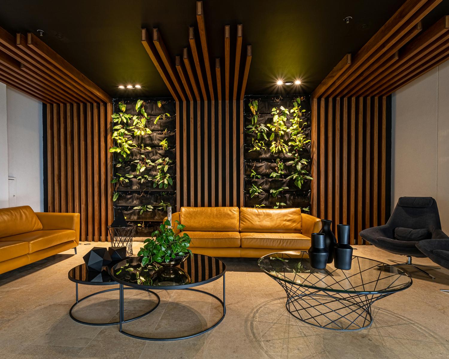 Salon avec canapés en cuir, lattes de bois et murs végétaux